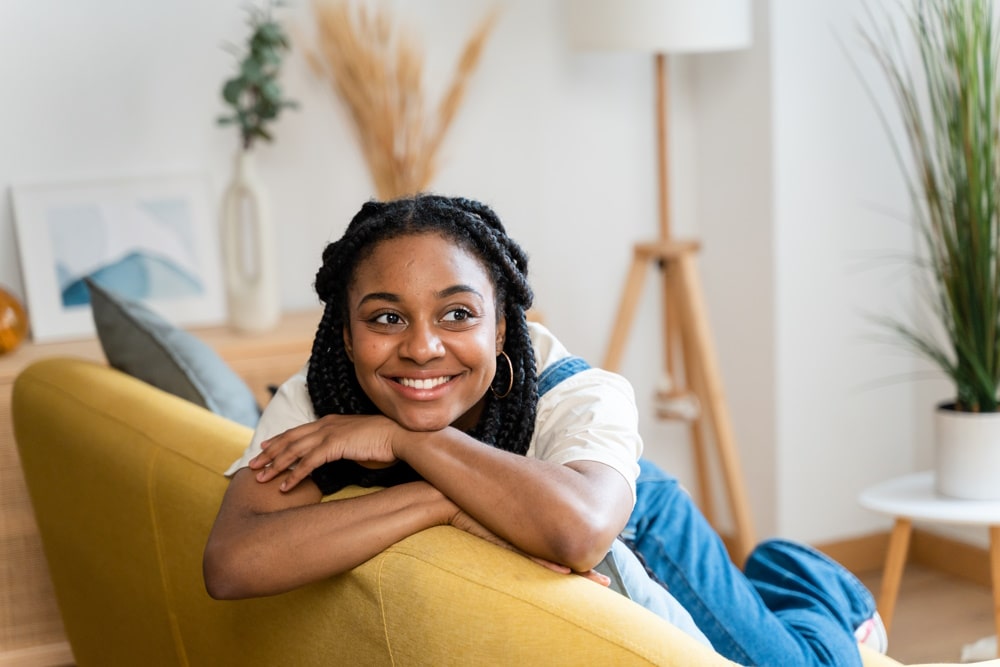 young lady leaning over sofa smiling after hypnotherapy for anxiety